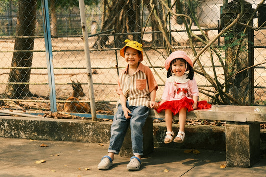 Two smiling children sitting on a bench outdoors