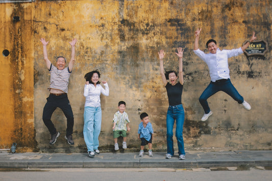 A happy family jumping in front of a textured wall.