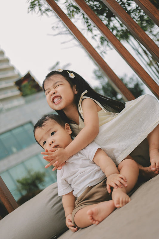 Two young siblings playing together outdoors.