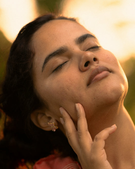 A woman with eyes closed touches her face.