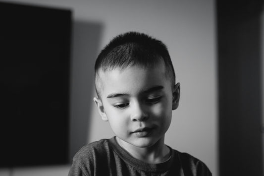 A young boy looking down with eyes closed