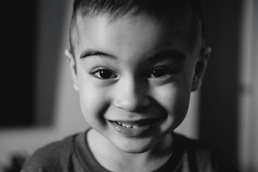 A young boy smiles warmly at the camera