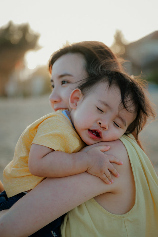 Mother holding sleeping baby on shoulder outdoors
