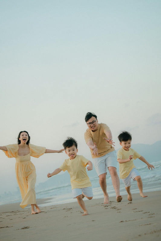 A family runs happily on a beach at sunset.