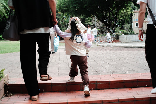 A child holds hands walking up stairs with adults.