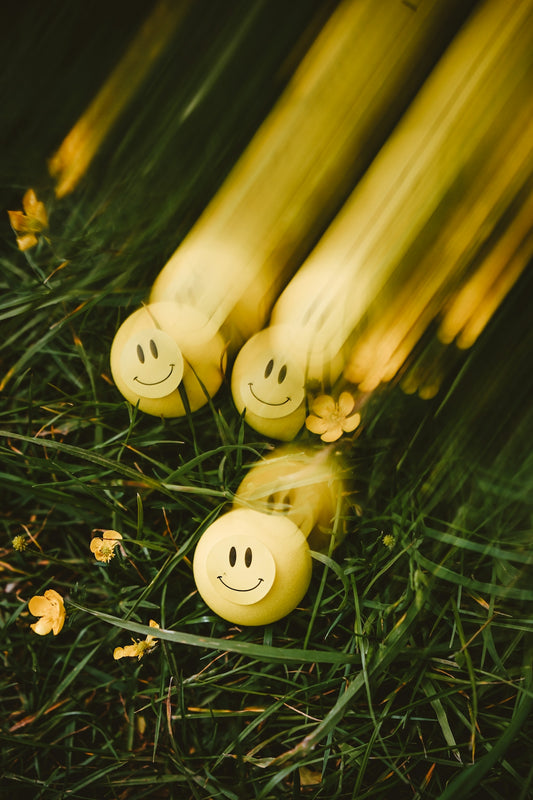 Yellow smiley balls rolling on green grass