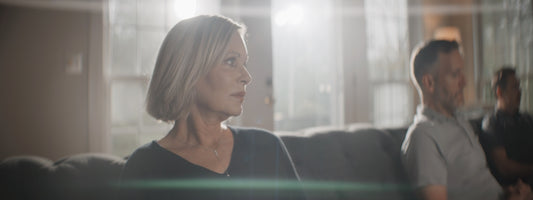 Woman and man sitting on a couch in sunlit room.