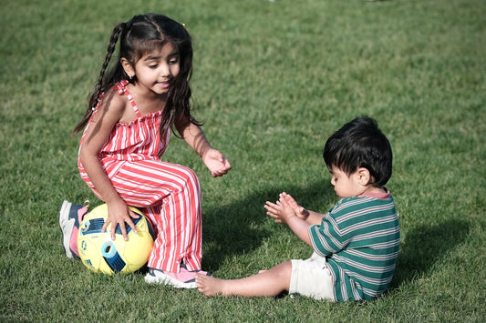 Children playing with a soccer ball on vibrant green grass.
