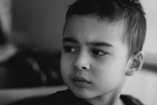 A young boy in black and white looking thoughtfully aside.