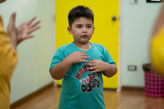 A young boy in a teal t-shirt with hands over his chest