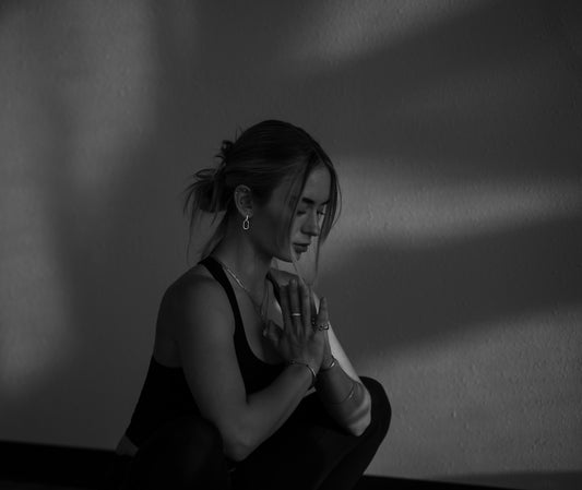 A woman in a black tank top with hands pressed together in prayer